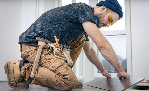 Ein männlicher Arbeiter legt Laminatboden auf den Boden