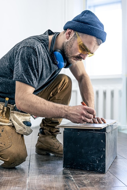 Ein männlicher Arbeiter legt Laminatboden auf den Boden