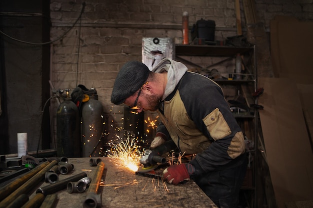 Ein männlicher Arbeiter schneidet Metall mit einem Handschleifer, helle Funken fliegen unter der Säge in alle Richtungen hervor.