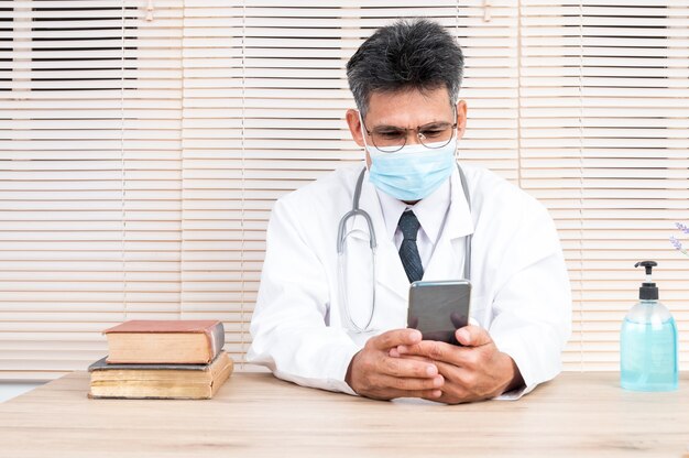 Ein männlicher Arzt, der eine Maske trägt, führt einen Videoanruf mit einem Patienten, um Ratschläge zu geben.
