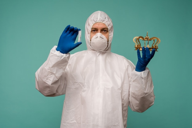 Ein männlicher Arzt in Schutzoverall und Maske hält eine Ampulle mit einem Impfstoff und einer Krone in den Händen. Coronovirus-Schutzkonzept in China.