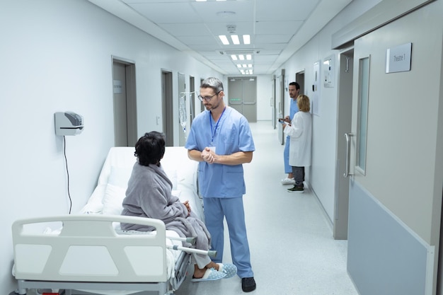 Ein männlicher Arzt interagiert mit einer behinderten Patientin im Flur