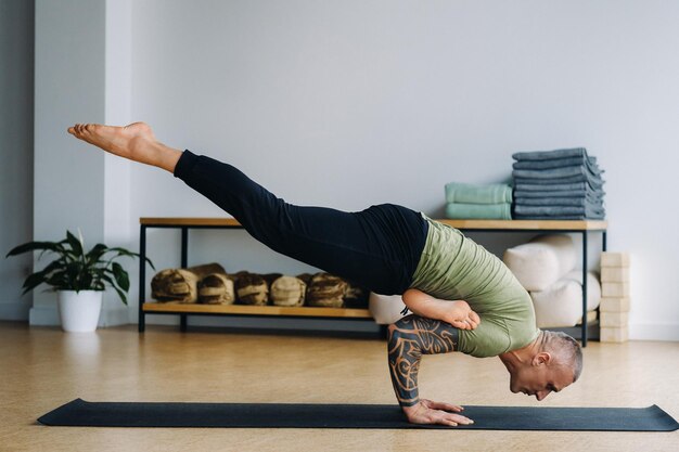 Ein männlicher Athlet in einem grünen T-Shirt macht Yoga im Fitnessstudio