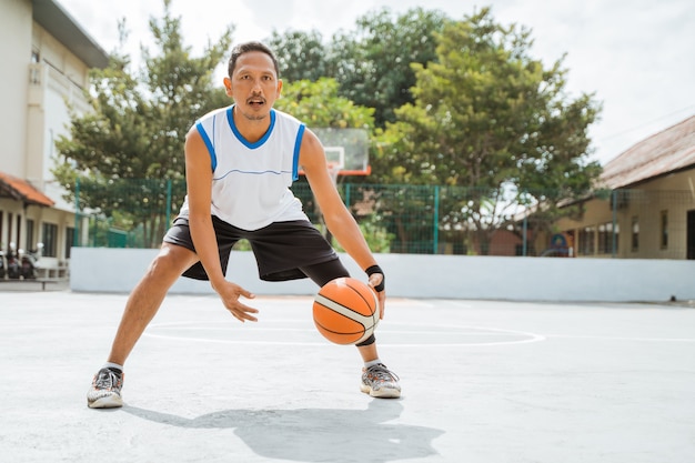 Ein männlicher Basketballspieler führt ein niedriges Dribbling mit dem Ball aus, während er Basketball übt