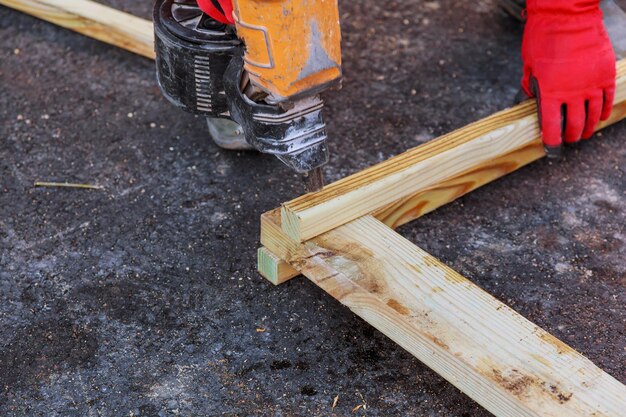 Ein männlicher Bauunternehmer arbeitet mit einer Holzplatte und einem Schneider auf dem Boden, eine Nahaufnahme der Hände eines reifen Handwerkers