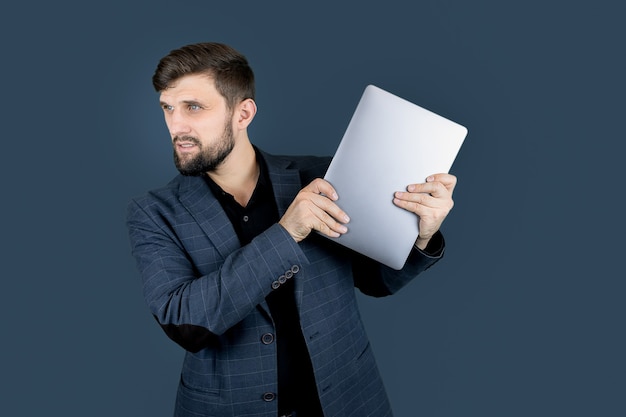 Ein männlicher Geschäftsmann in einem blauen Anzug hält einen Laptop