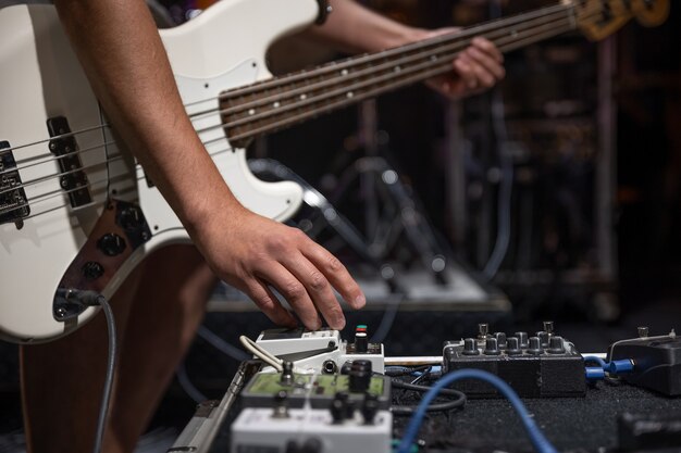 Ein männlicher Gitarrist, der auf der Bühne Gitarren-Audio-Verarbeitungseffekte einrichtet.