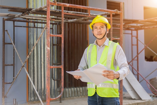 Ein männlicher Ingenieur betrachtet den Grundriss auf der Baustelle.