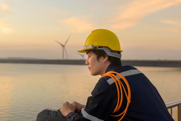 Ein männlicher Ingenieur, der bei Sonnenuntergang einen Schutzhelm trägt.