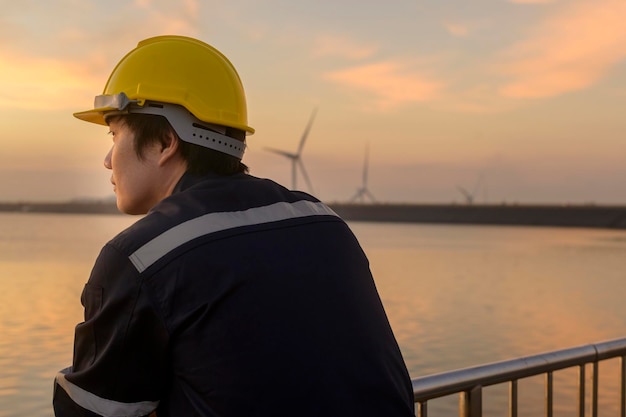 Ein männlicher Ingenieur, der bei Sonnenuntergang einen Schutzhelm trägt.