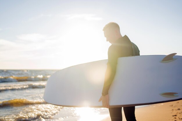 Ein männlicher Surfer im Neoprenanzug lernt im Urlaub das Surfen auf den Wellen im Meer