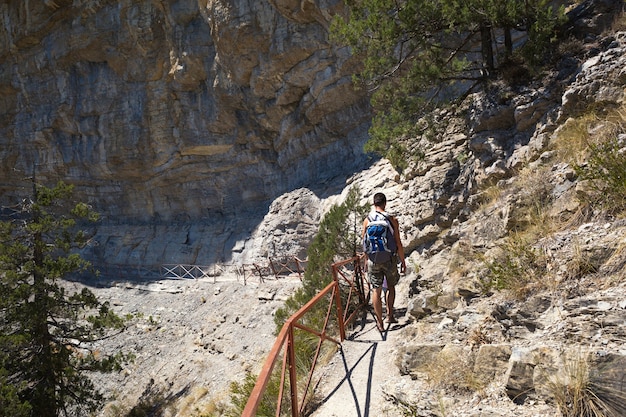 Ein männlicher Tourist mit einem Rucksack geht einen Pfad in den Bergen entlang. Reisen, Trekking,