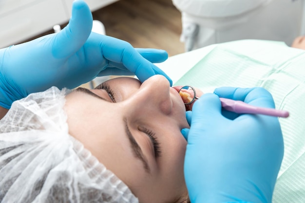 Ein männlicher Zahnarzt betrachtet einen Kiefer einer weiblichen Patientin und überprüft den Biss