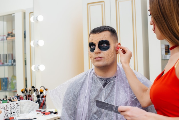 Ein Make-up-Spezialistin macht für den Halloween-Urlaub im Studio ein festliches, gruseliges Make-up für einen Mann. Glückliches Halloween-Konzept.