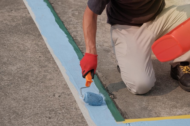 Ein Maler, der auf einem Parkplatz blaue Streifen auf Parkplätzen malt