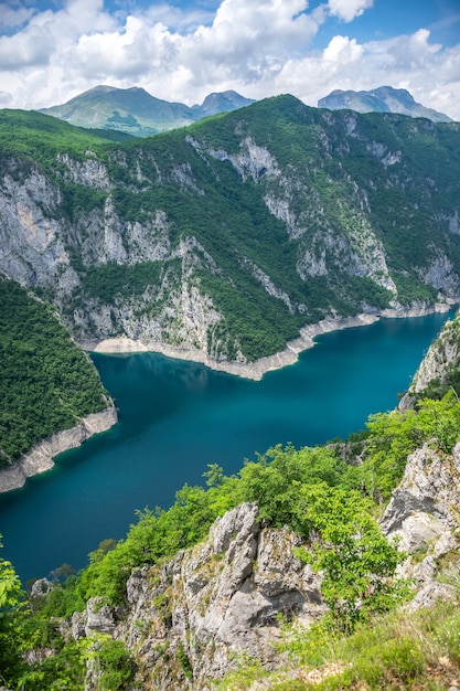 Ein malerischer türkisfarbener See kann von der Spitze eines hohen Berges aus gesehen werden.