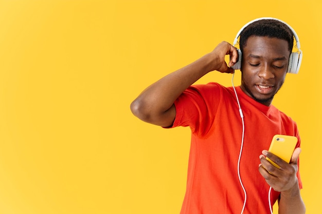 ein Mann afrikanischen Aussehens in einem orangefarbenen T-Shirt mit Kopfhörern in hoher Qualität Foto