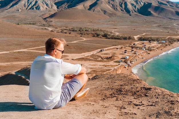 Ein Mann am Kap Chamäleon und bewundert einen atemberaubenden Panoramablick auf die Hügel und das Meer aus großer Höhe