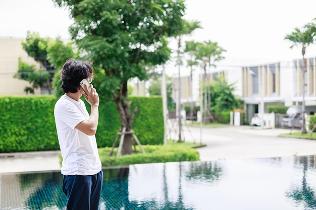 Ein Mann arbeitet im Urlaub fern und nutzt das Smartphone in der Nähe des Swimmingpools im Resorthotel