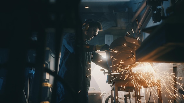 Foto ein mann arbeitet mit einer kreissäge, ein arbeiter schleift metall in der werkstatt, funken fliegen aus heißem metall.