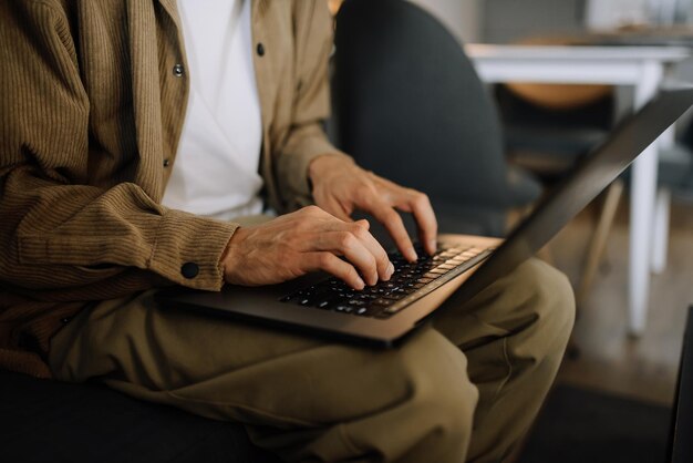 Foto ein mann arbeitet zu hause an einem laptop auf seinem schoß. hände auf laptop-nahaufnahme