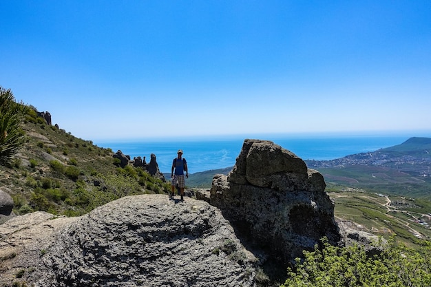 Ein Mann auf dem Hintergrund des Plateaus der Krimberge und des Schwarzen Meeres von der Spitze des Demerji Russland