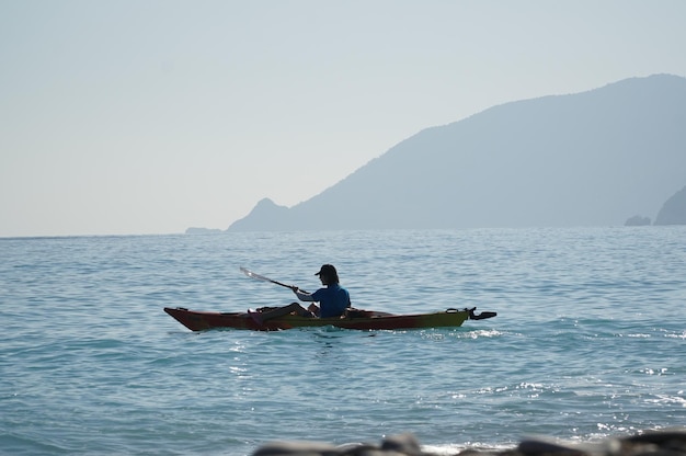 Foto ein mann auf einem kajak im meer mit bergen im hintergrund