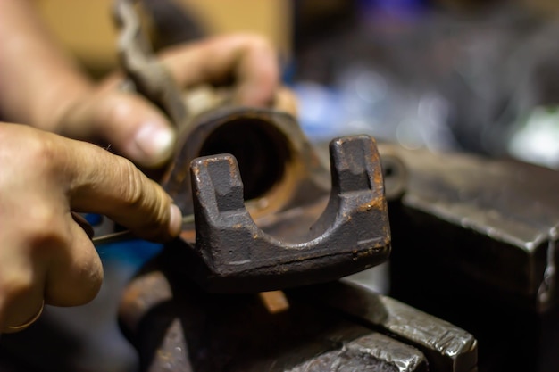 Ein Mann bearbeitet mit einem Hammer ein Stück Metall.