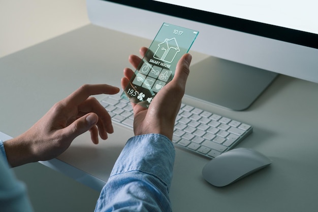 Ein Mann benutzt ein futuristisches transparentes Telefon mit Anwendung zur Steuerung von Smart House.