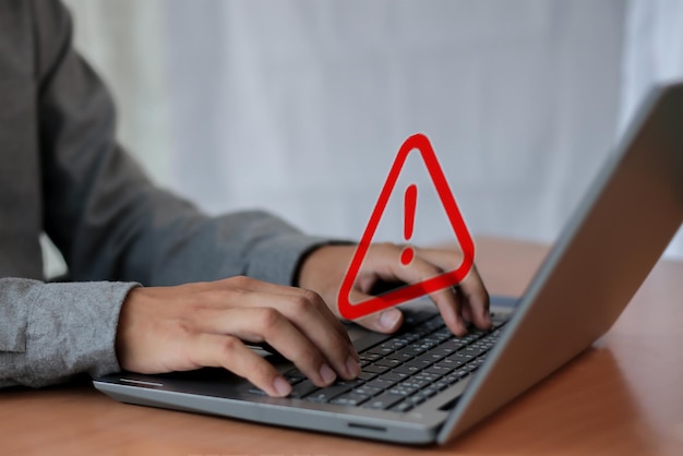 ein Mann benutzt einen Laptop mit einem roten Dreieck auf dem Bildschirm