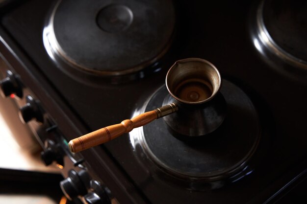 Ein Mann bereitet schwarzen Kaffee auf einem elektrischen Herd vor und braut Kaffee in einem türkischen Kaffeekannen.