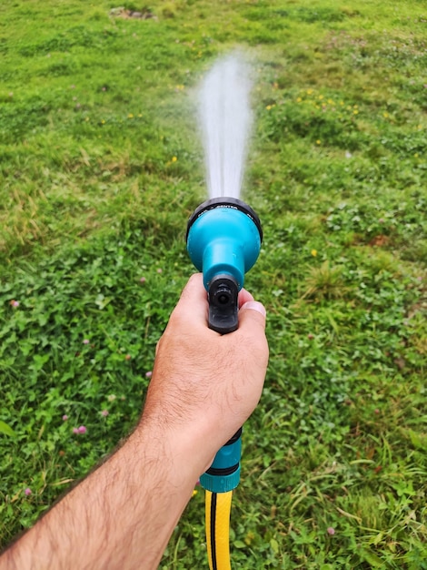 Ein Mann bewässert seinen Rasenhof mit einem Handsprinkler