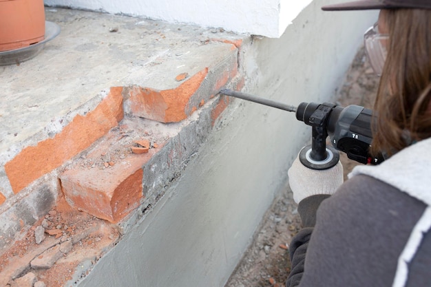 Foto ein mann bricht einen ziegelstein vom fundament. demontage der zerstörten ziegel. restaurierung des hauses.