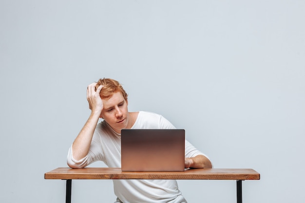 Ein Mann, der an einem Laptop auf einem hellen Hintergrund arbeitet