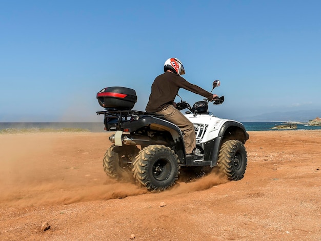 Ein Mann, der ATV im Sand mit Schutzhelm fährt