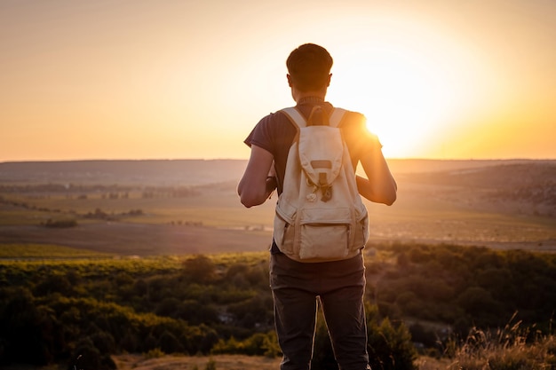 Ein Mann, der auf einem Berg steht, während die Sonne untergeht