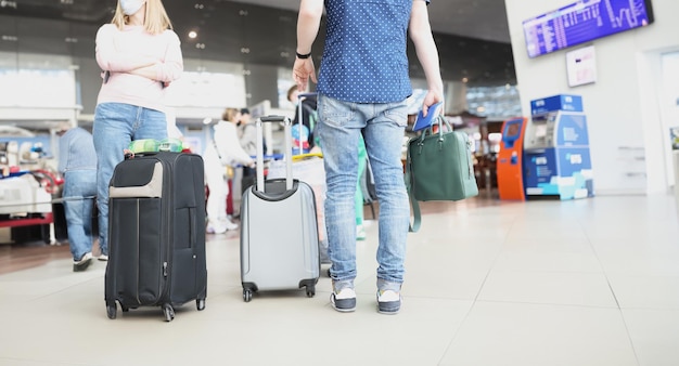 Ein Mann, der auf Reise ist und eine Flugverzögerung hat, steht in der Schlange, um sich im Flughafen-Terminal einzuschecken