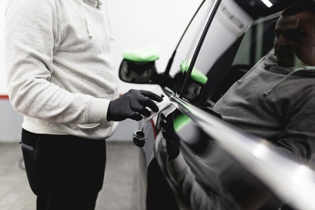 Ein Mann, der Auto, Autodetaillierungs- (oder Reinigungskonzept) säubert Selektiver Fokus.