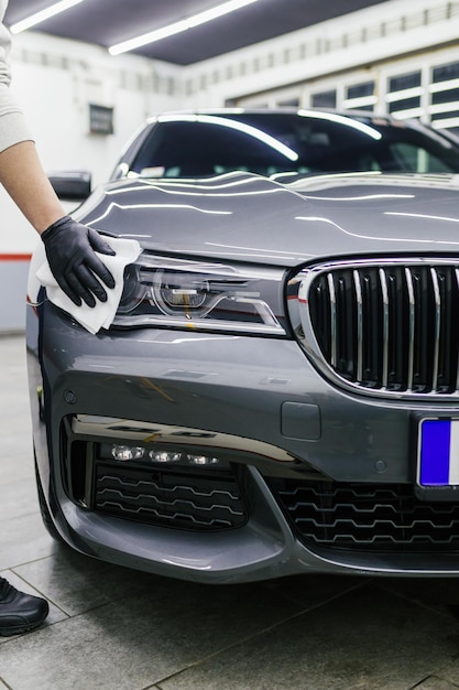 Ein Mann, der Auto mit Mikrofasertuch, Autodetaillierungs- (oder Reinigungskonzept) säubert. Selektiver Fokus.