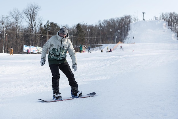 Ein Mann, der bergab Snowboard fährt, steht kurz davor, die Skipiste hinten anzuhalten