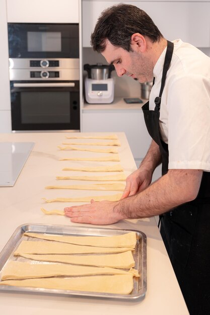 Ein Mann, der Croissants kocht und die dreieckigen Schnitte aus der Blätterteigarbeit zu Hause aufnimmt