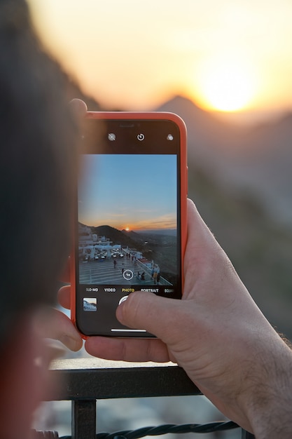 Ein Mann, der ein Foto des Sonnenuntergangs in einigen Bergen macht