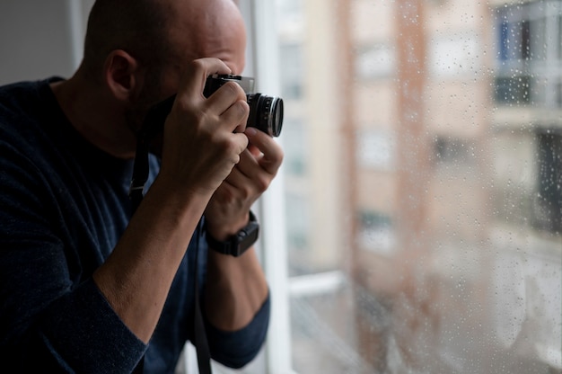 Ein Mann, der ein Foto mit analoger Kamera durch ein Fenster macht