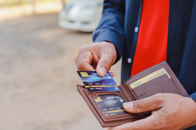 Ein Mann, der ein Telefon, eine Kreditkarte und eine Brieftasche hält