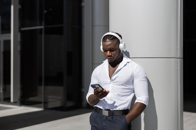 Ein Mann, der ein weißes Hemd und eine schwarze Hose trägt, benutzt sein Telefon und schaut auf sein Telefon.