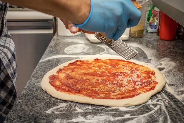 Ein Mann, der eine Margherita-Pizza in einem lokalen Pizza- und Gyros-Restaurant macht