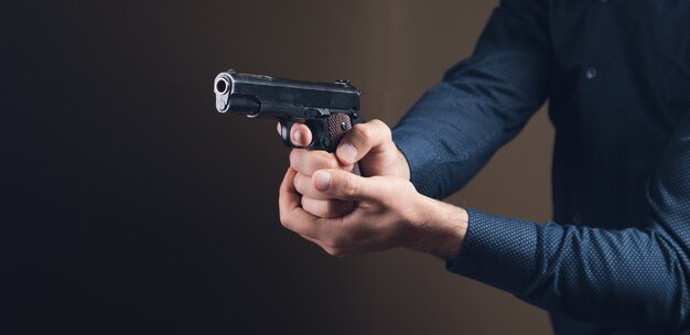 Ein Mann, der eine schwarze Pistole in der Hand hält, droht