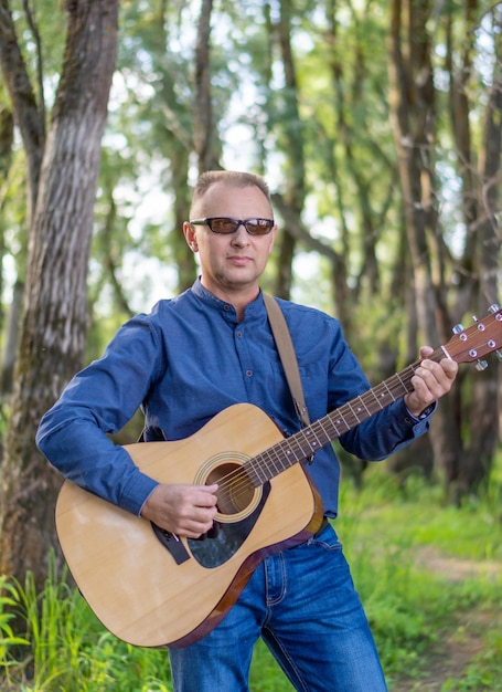Ein Mann, der im Wald Gitarre spielt