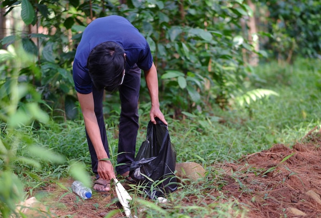 Ein Mann, der im Wald Plastikmüll aufsammelt