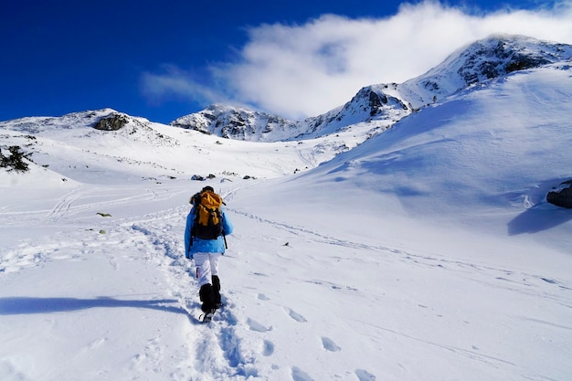 Ein Mann, der im Winter auf einem Berg spazieren geht, in voller Länge